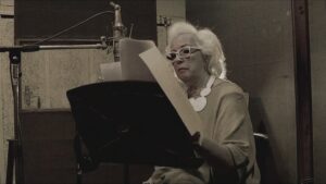 Susana Rinaldi lee frente a un micrófono en una imagen del documental