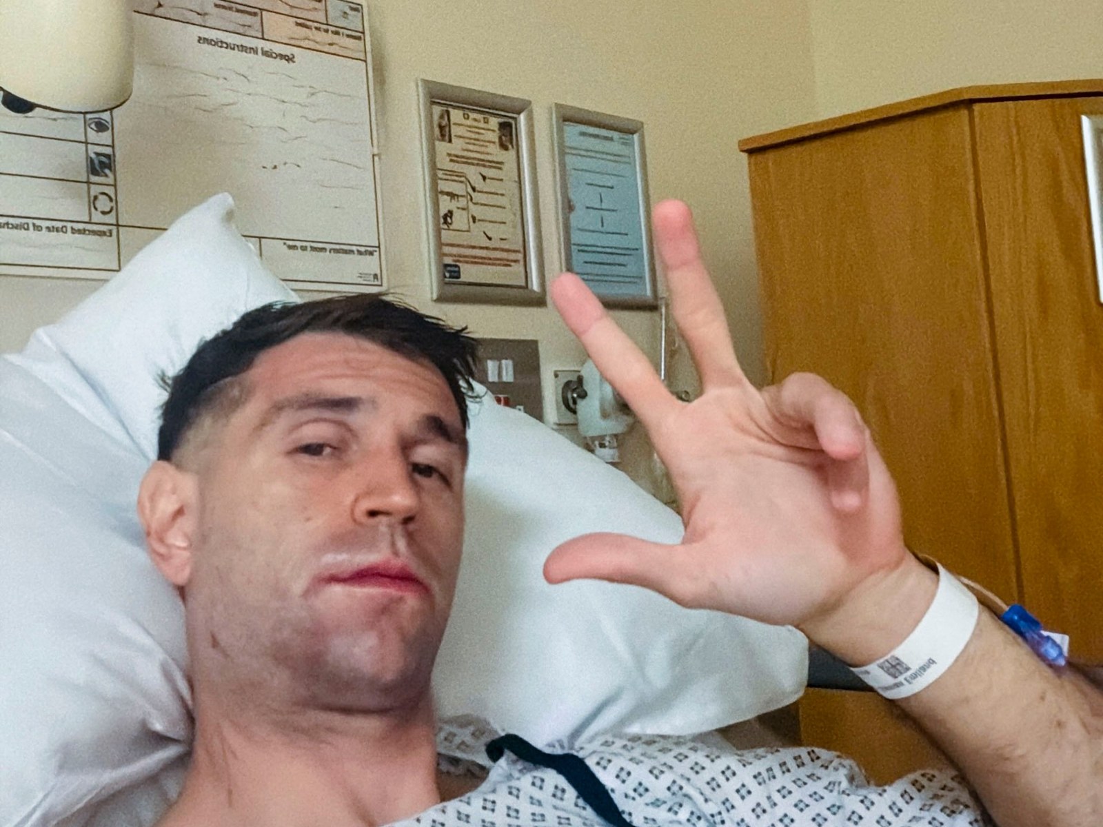 Emiliano "Dibu" Martínez en una cama de hospital, haciendo la señal de la victoria con la mano, tras ser operado de la mandíbula.