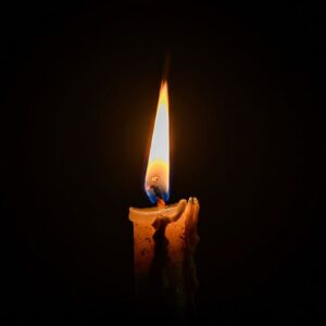 Vela encendida sobre fondo oscuro, imagen ilustrativa.