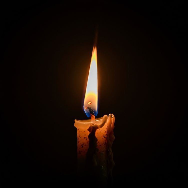 Vela encendida sobre fondo oscuro, imagen ilustrativa.