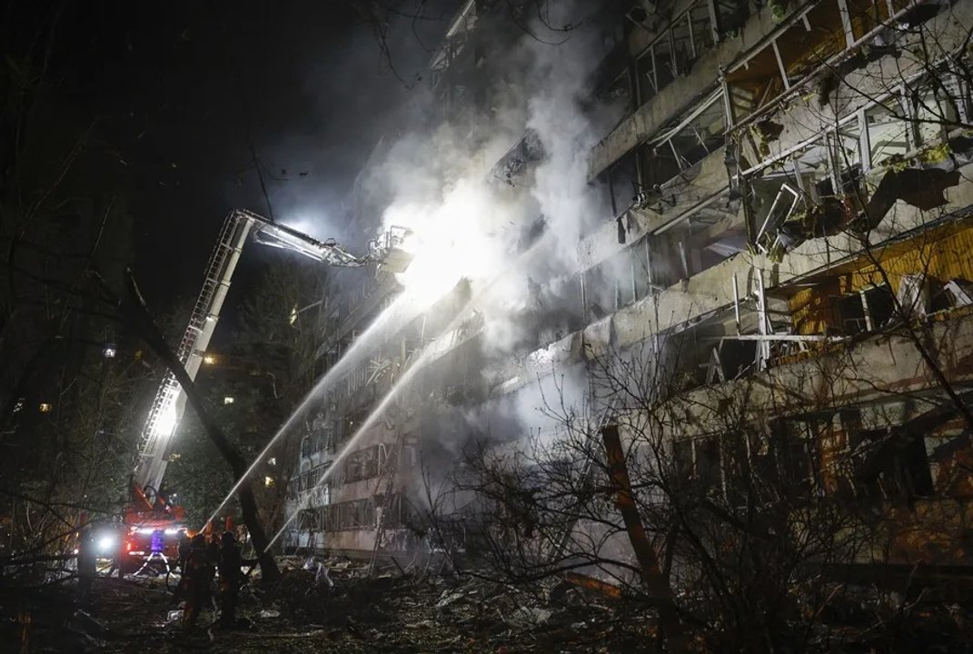 Bomberos trabajan de noche en un edificio dañado tras el ataque ruso contra la infraestructura energética de Kiev.