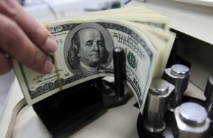 Una persona cuenta billetes de 100 dólares en una casa de cambio.
