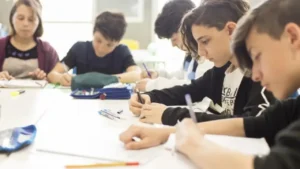 Estudiantes escriben en un aula durante una clase.