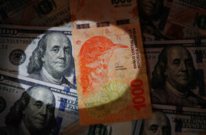 Un billete de mil pesos argentinos sobre billetes de cien dólares (foto ilustrativa de archivo).