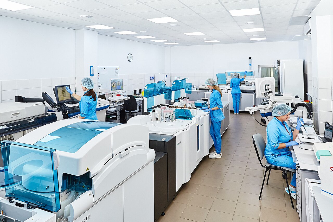 Grupo de científicos con guardapolvo y guantes trabajando en un laboratorio